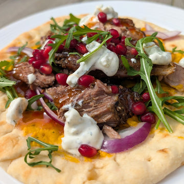 Moroccan-Style Slow-Roasted Lamb Shoulder on Warm Flatbread with Hummus, Tzatziki, Sweet Chilli Sauce, Fresh Salad & Pomegranate Seeds