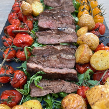 Steak Tagliata with roasted vine tomatoes, peppery rocket salad & herby roasted potatoes